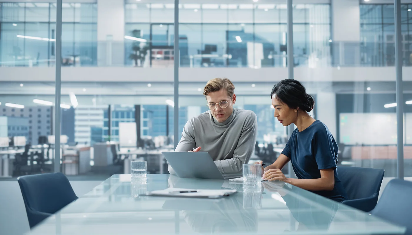 Finance team in modern boardroom reviewing costs on a laptop