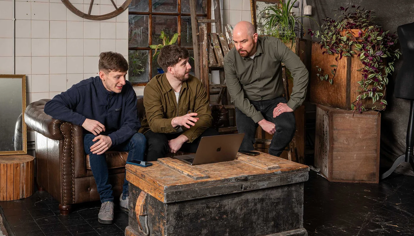 ecommerce agency team sat on a sofa having a discussion in front of a laptop