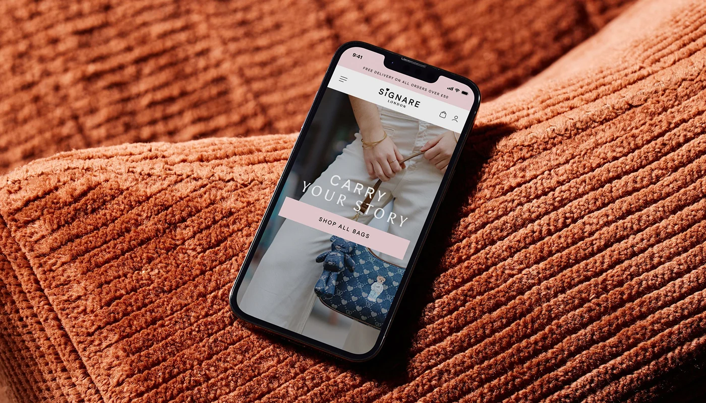 mobile phone on orange sofa displaying modern fashion ecommerce store