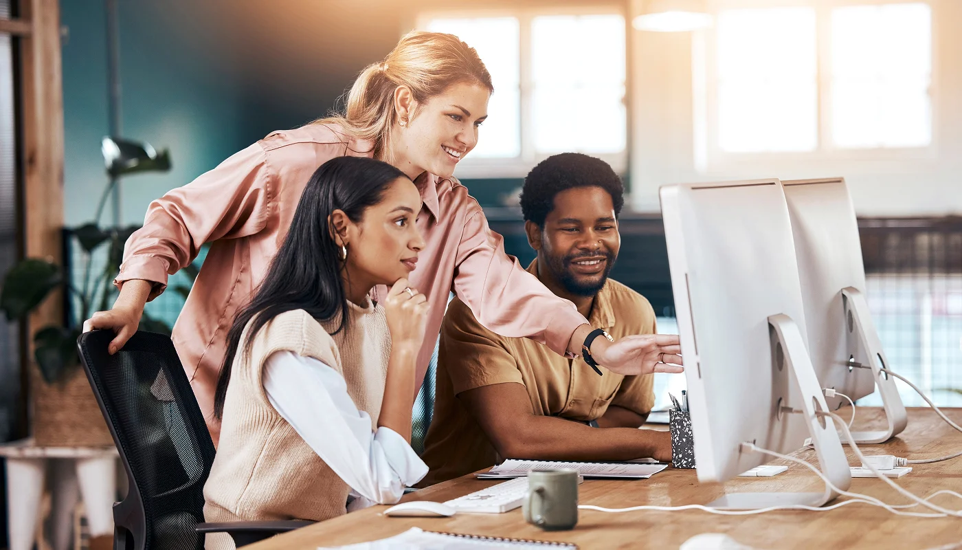 marketing team around a desktop computer reviewing content