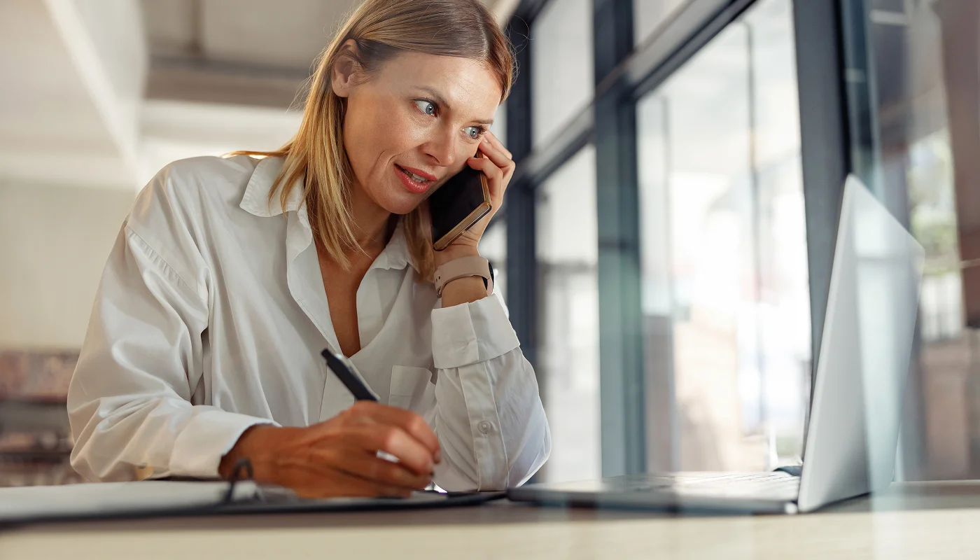 Professional making notes whilst on a call checking her website