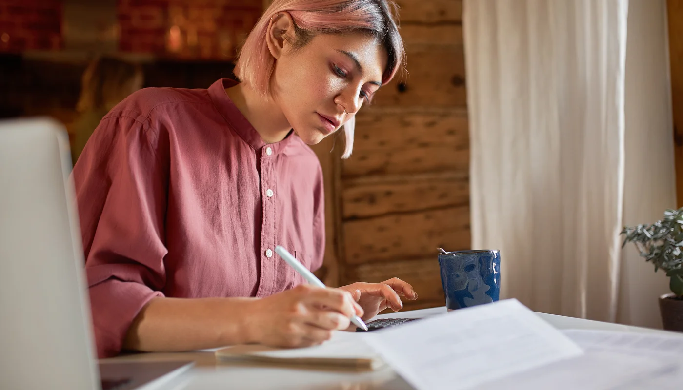 content writer at desk making notes with pen and paper