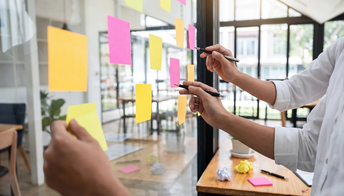 post-it notes being stuck on a glass board for planning
